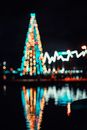 夜间，模糊的圣诞树灯光倒映在水中，营造出节日的氛围
