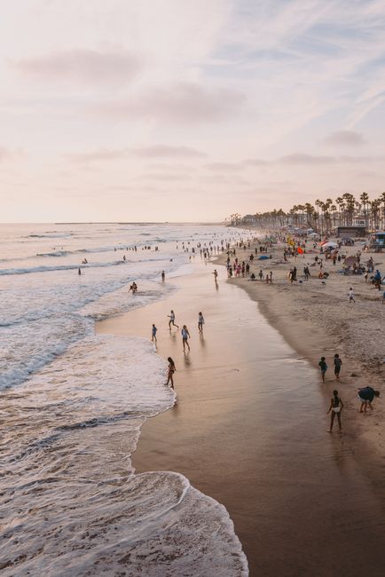 A peaceful sunset beach scene with people enjoying the waves, under a calming sky.
