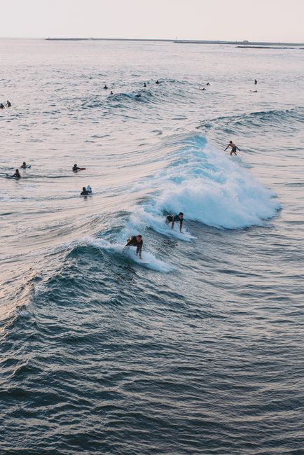 An aerial shot of surfers catching waves on a sunny day at the coast.