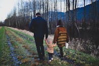 一个凉爽的秋日，一家人手牵手沿着森林小径散步