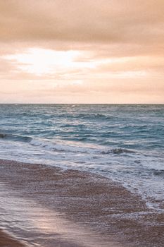 Serene beach scene capturing gentle waves at sunset, offering a tranquil seaside view.