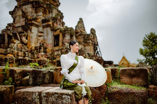 Smiling Model in a White Chiffon Embroidered Blouse with a Green Sash and a Green Silk Printed Sampot Skirt in Ruins of Angkor Wat