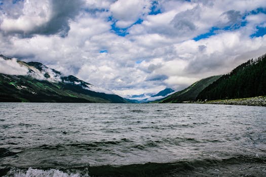 Explore the dramatic scenery of a mountain lake under a cloudy sky, capturing serene nature.
