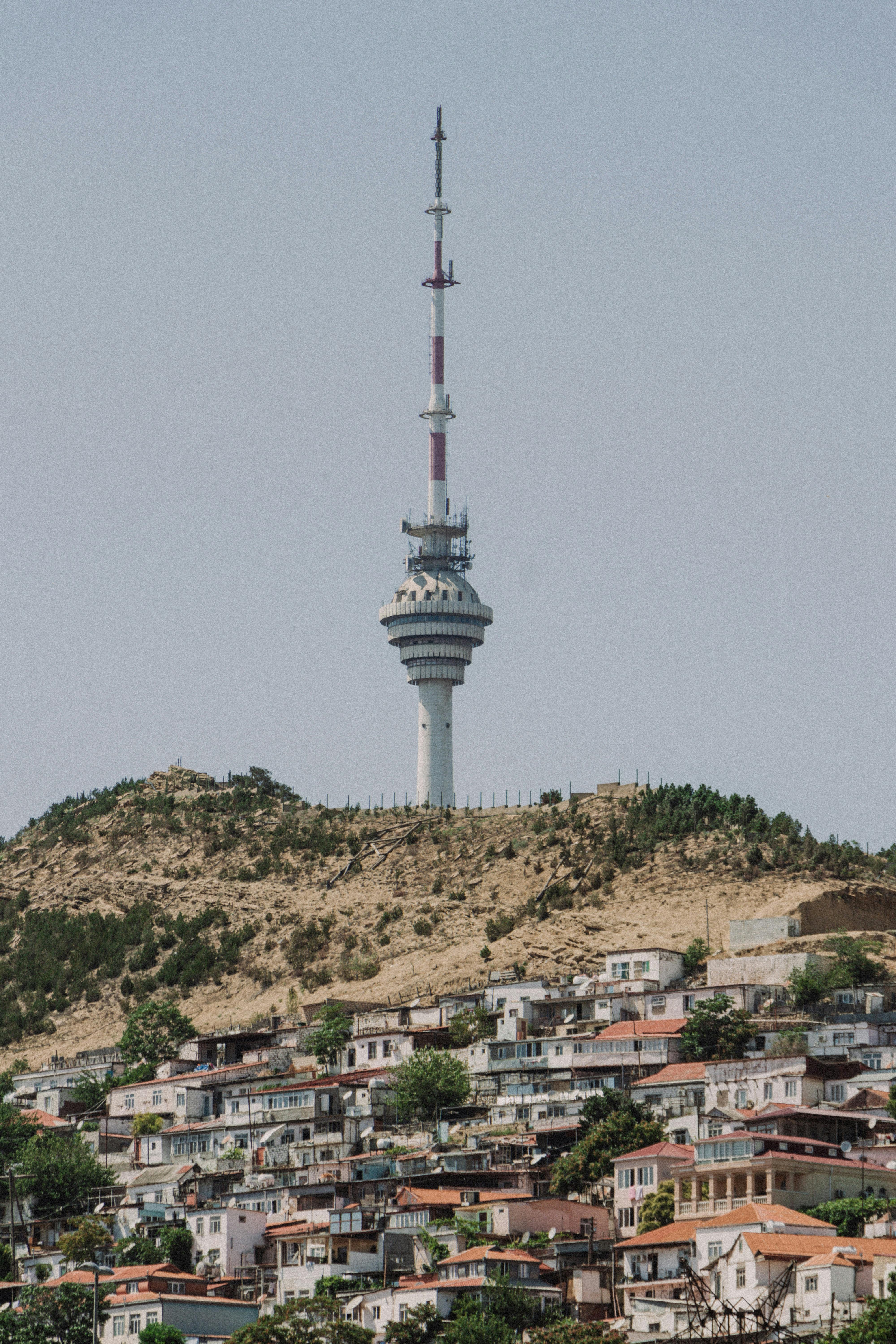 Television tower on a hill above townhouses on a sunny day, scenic landscape.