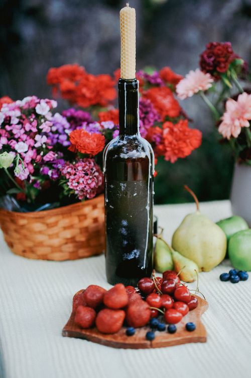 Free Vibrant still life of fruits and flowers with a wax candle on a bottle, perfect for rustic decor. Stock Photo