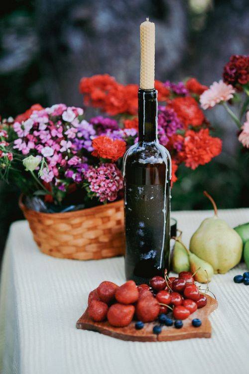 Free Colorful summer table with fresh fruit, flowers, and a wine bottle candle holder outdoors. Stock Photo