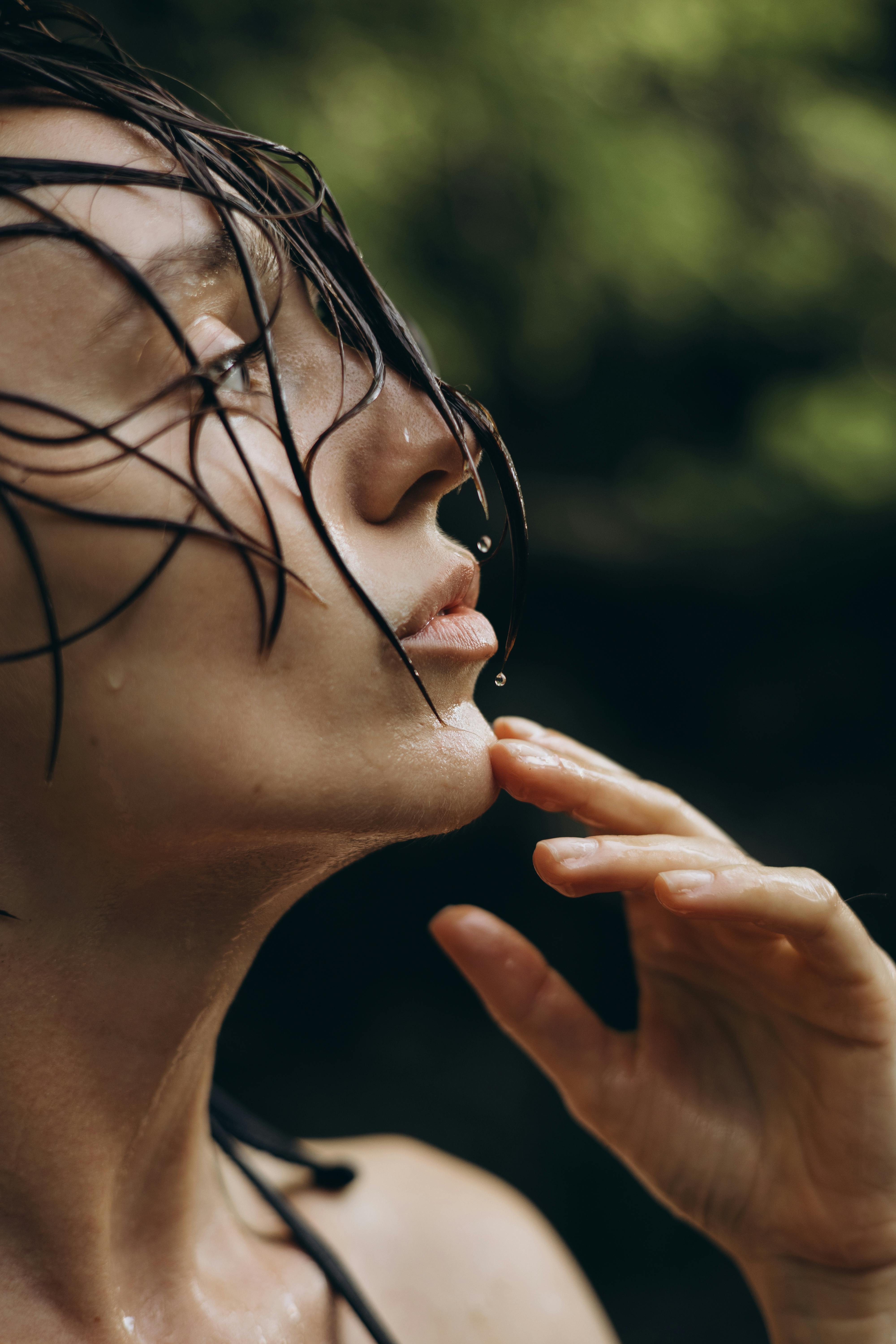 A striking close-up portrait of a woman with wet hair, captured outdoors in natural light.