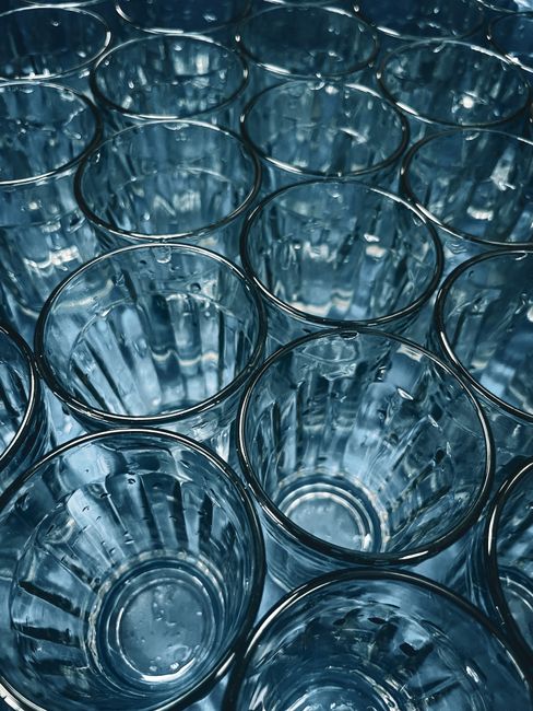 Close-up shot of multiple clear glasses arranged in a grid pattern, viewed from above.