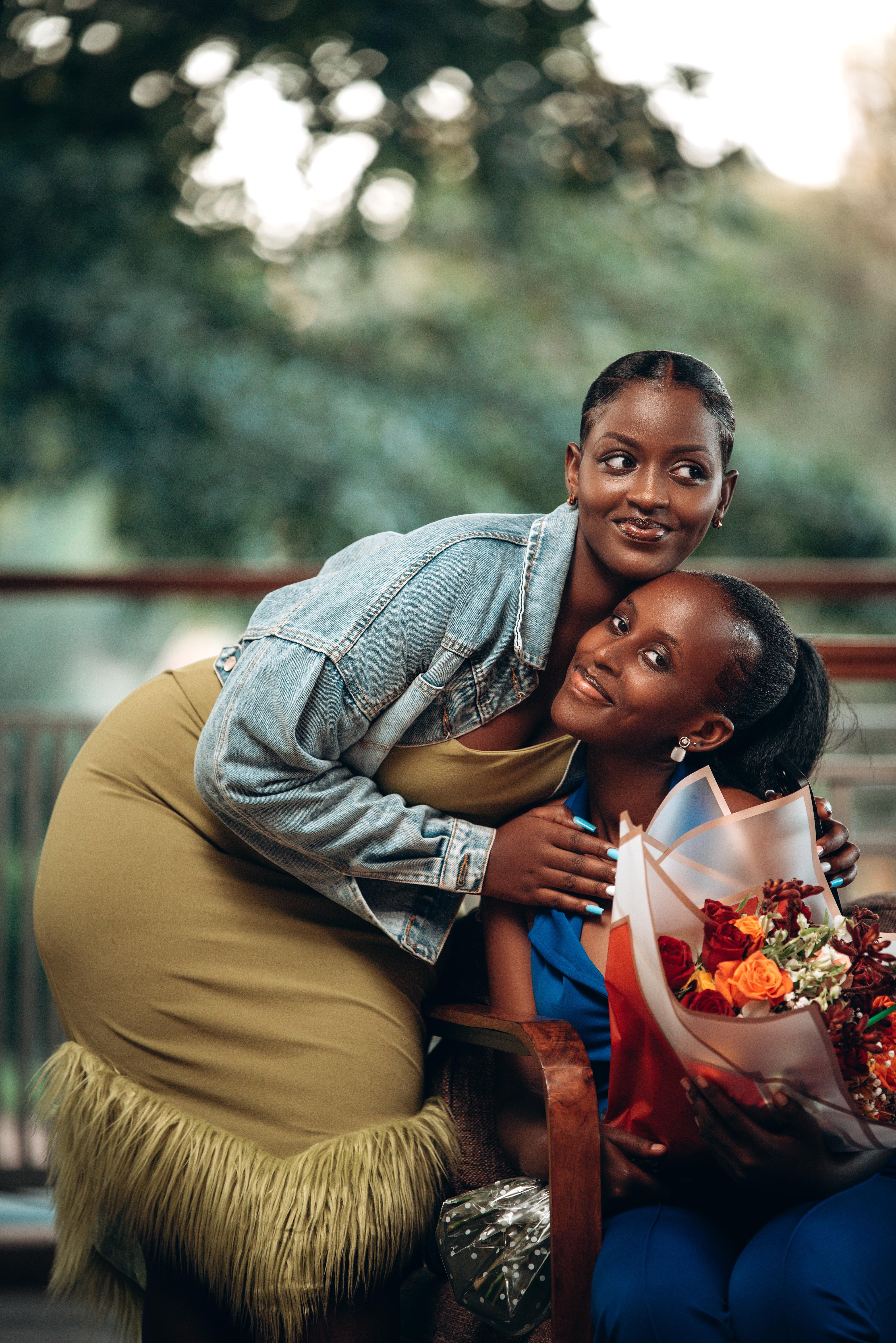 Women Embracing and Posing with a Bouquet of Flowers · Free Stock Photo