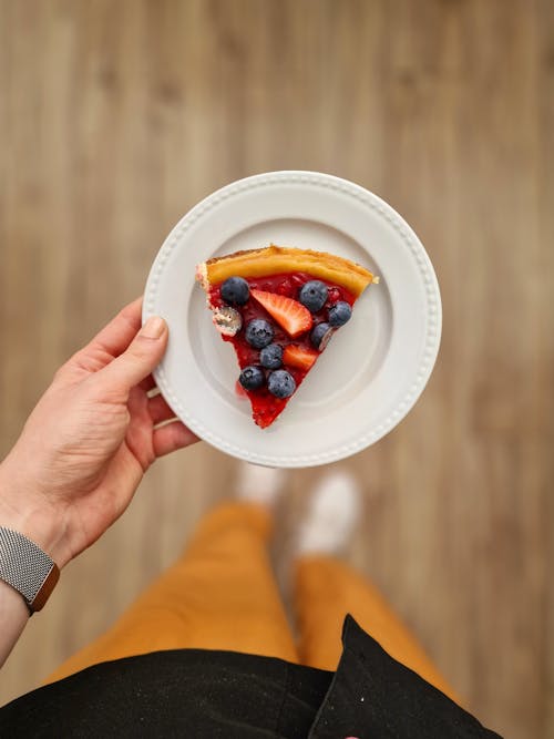 A Person Holding a Plate with a Slice of Cake 