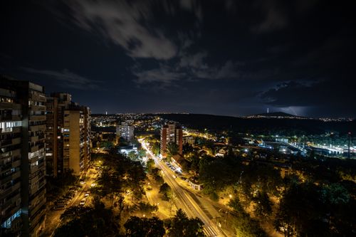 Free Aerial view of a city with dramatic sky and illuminated buildings at night. Stock Photo