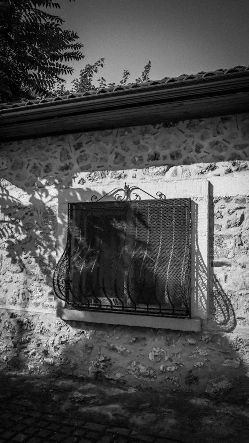 A Window with a Grill in a Stone House 