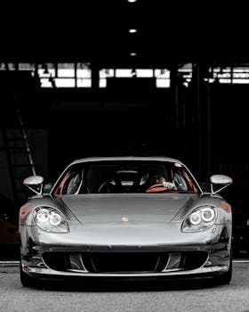 Front view of a sleek luxury sports car in a contemporary garage with dim lighting.