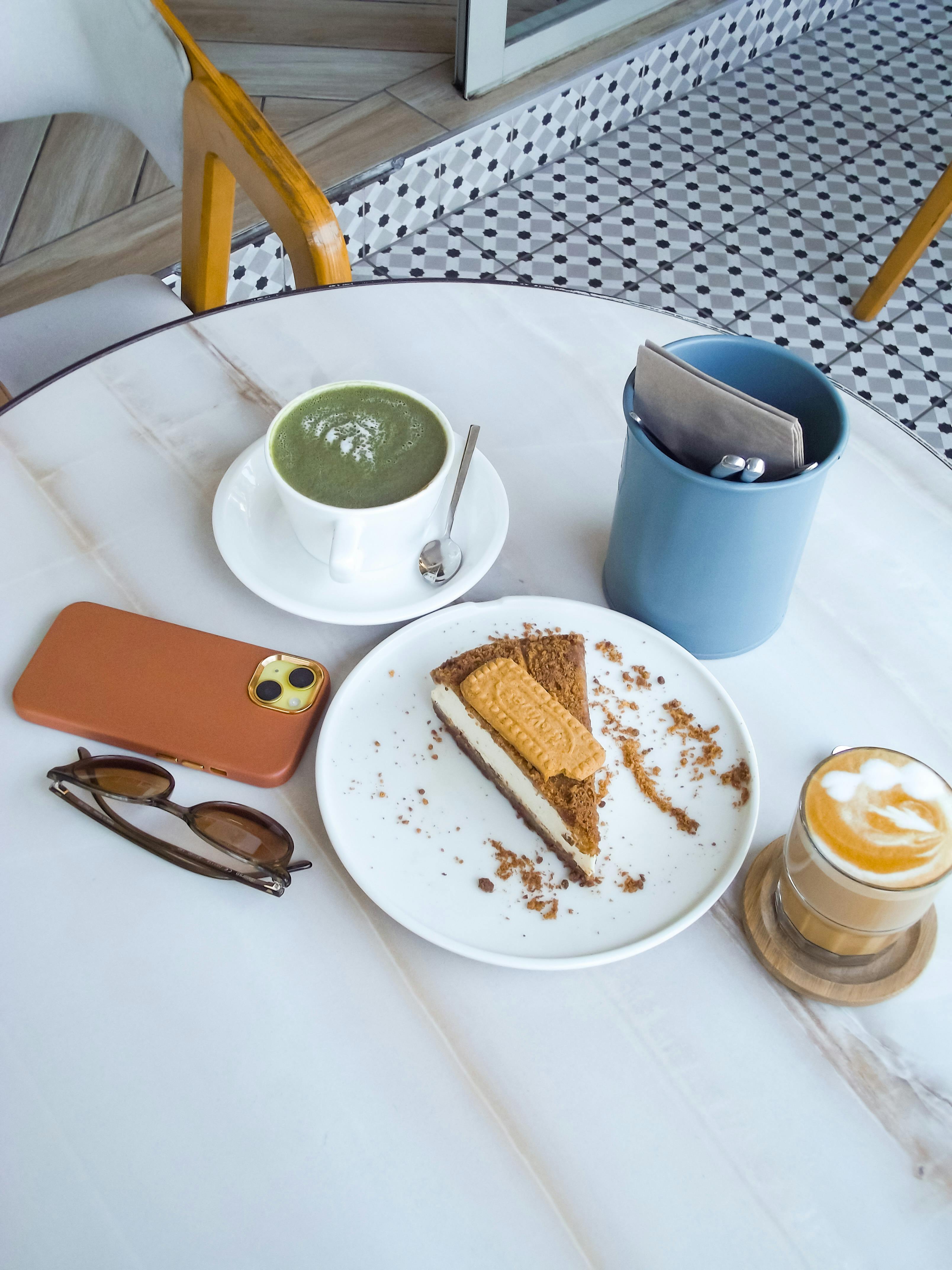 A cozy café table featuring matcha latte, dessert, and cappuccino for a relaxing break.