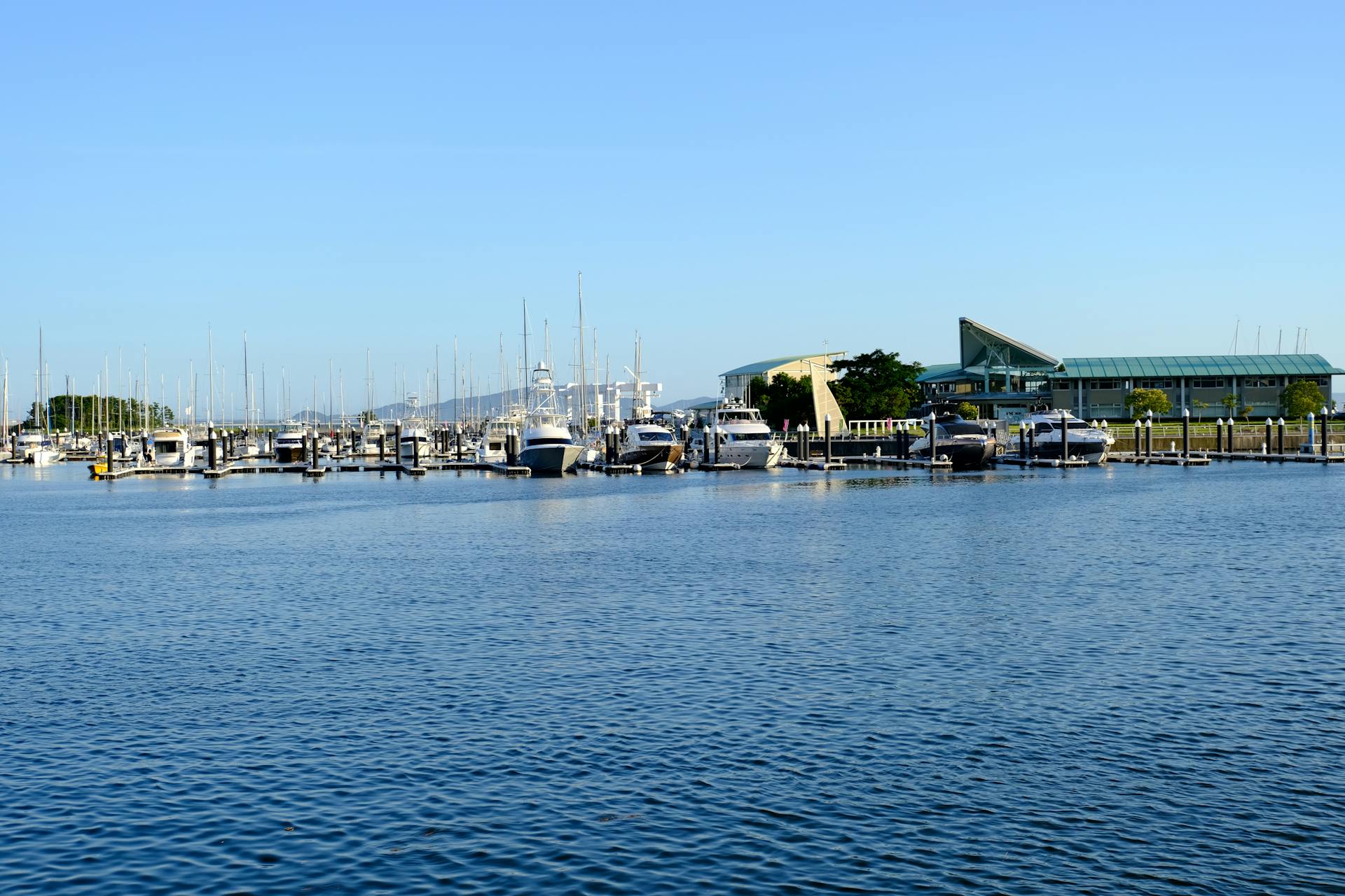 Tranquil marina scene in Gamagori, Aichi, Japan with docked yachts under a clear blue sky.
