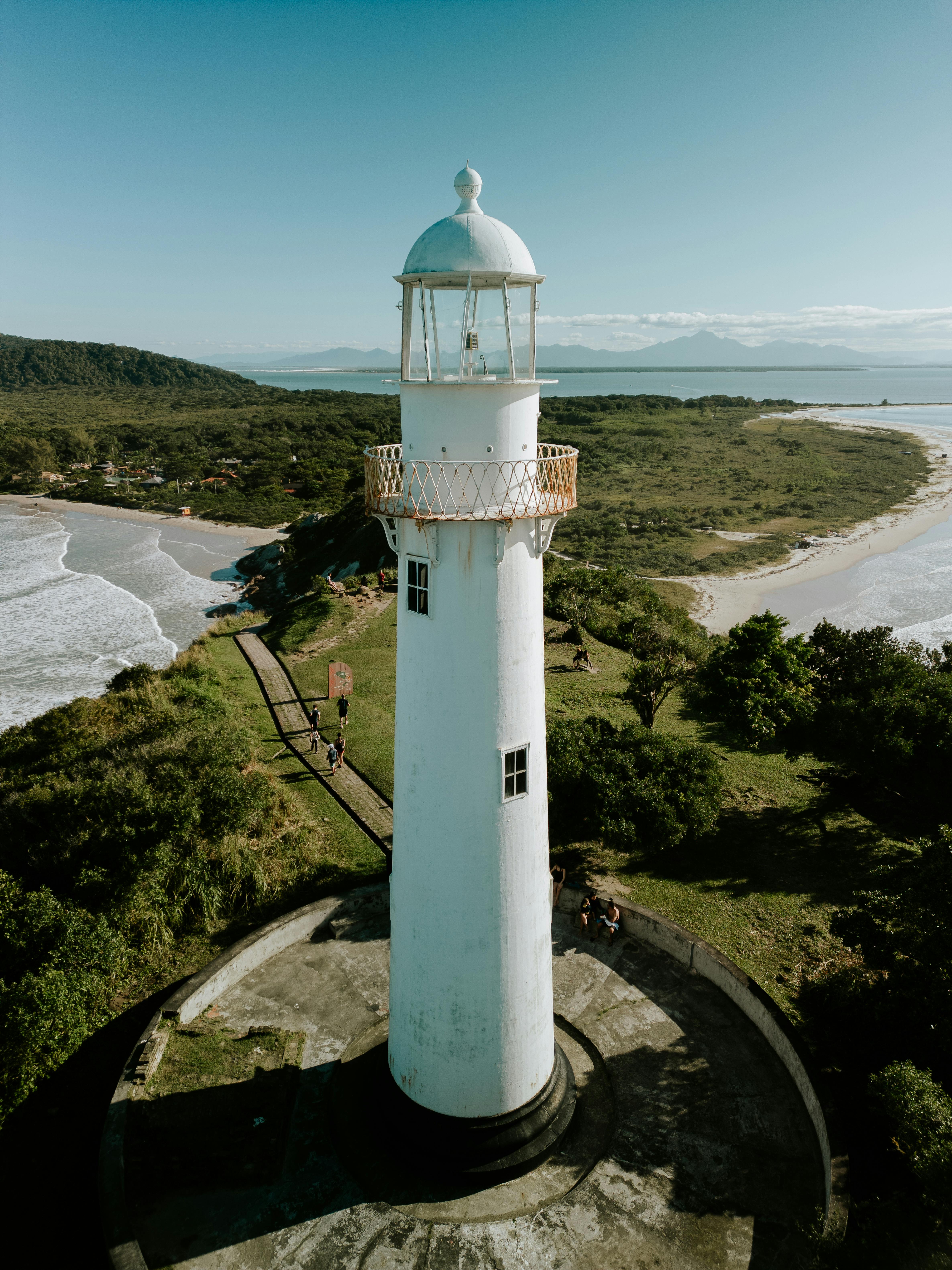 Dramatic birds eye view of white lighthouse overlooking a beautiful coastal landscape.