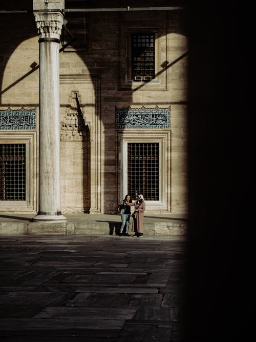 Free Two women engage in conversation beside a column at a historic Istanbul mosque. Stock Photo
