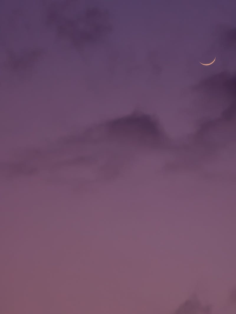 A serene crescent moon set against a vibrant purple sky at twilight