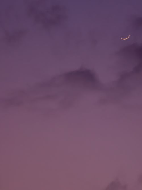 Free A serene crescent moon set against a vibrant purple sky at twilight. Stock Photo