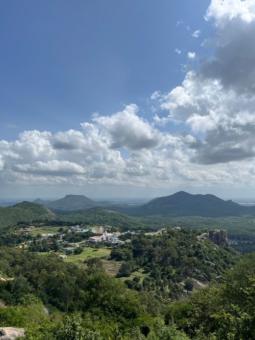 Free A breathtaking view of lush green hills and a small town under a cloudy blue sky. Stock Photo