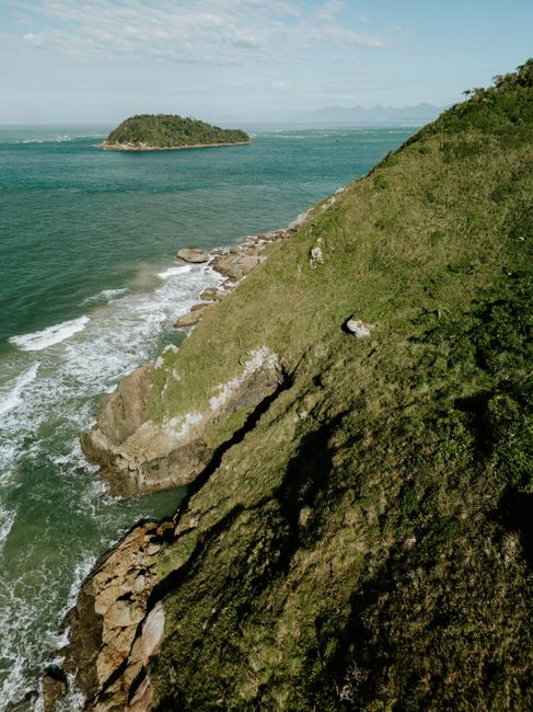 Stunning vertical view of a grassy cliffside meeting the ocean in Paranaguá, Brazil.