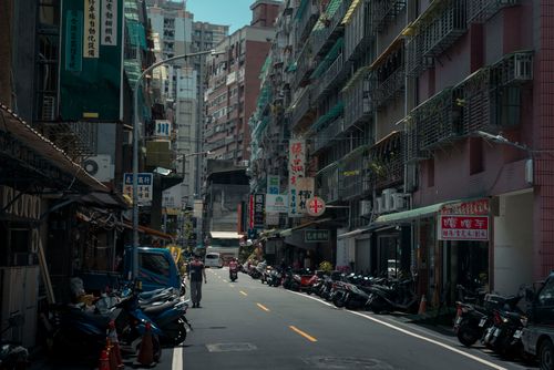Free A bustling urban street with lined motorcycles and towering old buildings. Stock Photo