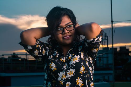 Free Indian woman with eyeglasses poses in floral shirt during a beautiful sunset. Stock Photo