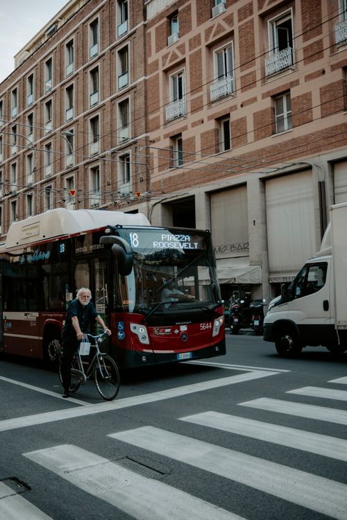 Free Busy city street in Italy with a bus, cyclist, and vehicles in motion. Stock Photo