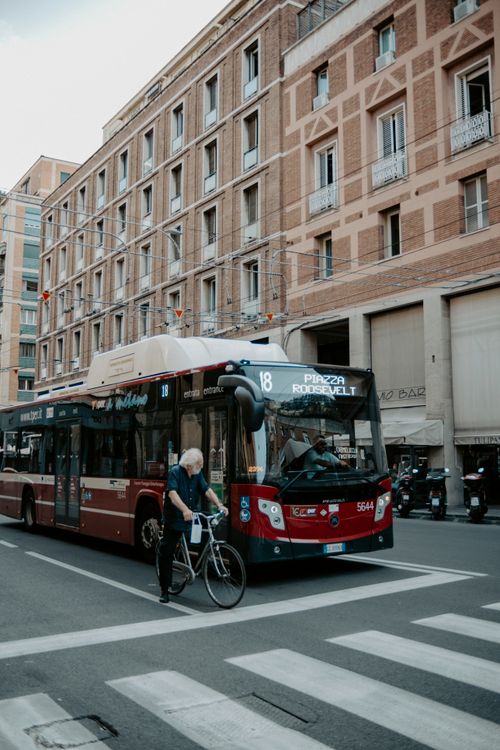 Free Bologna city street featuring a city bus, an old cyclist, and classic Italian architecture. Stock Photo