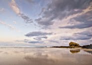 黄昏时分，美丽宁静的海滩与戏剧性的云彩倒映在潮湿的沙子上