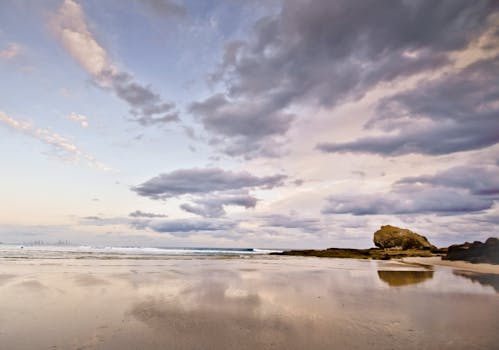黄昏时分，美丽宁静的海滩与戏剧性的云彩倒映在潮湿的沙子上