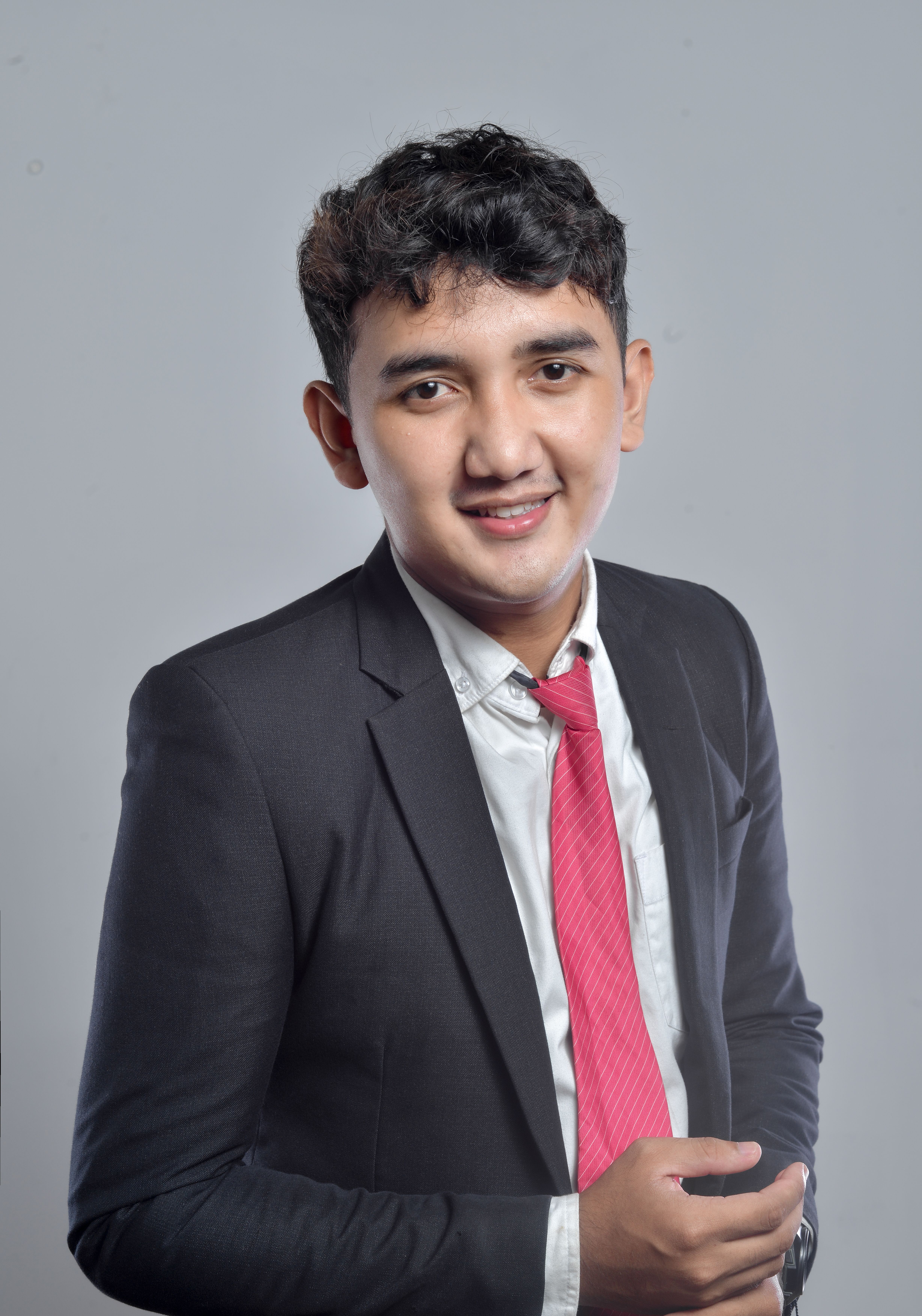 Portrait of a young businessman in a suit and red tie, smiling confidently.