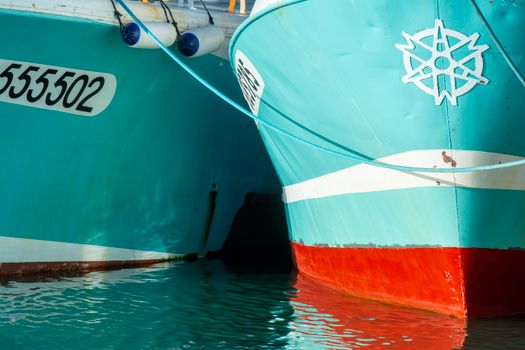 Close-up view of two colorful boats docked in a harbor, showcasing nautical design elements.