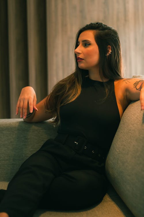 Young Woman in a Black Outfit Sitting on a Sofa 