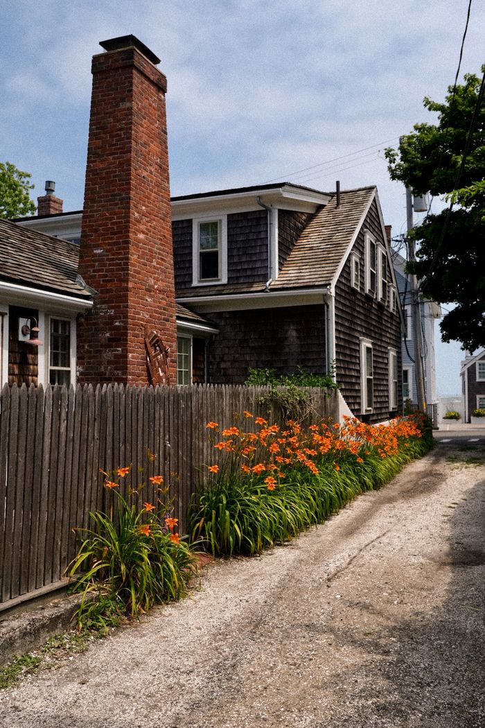 Historic New England house in Provincetown, Massachusetts, with summer flowers and a brick chimney