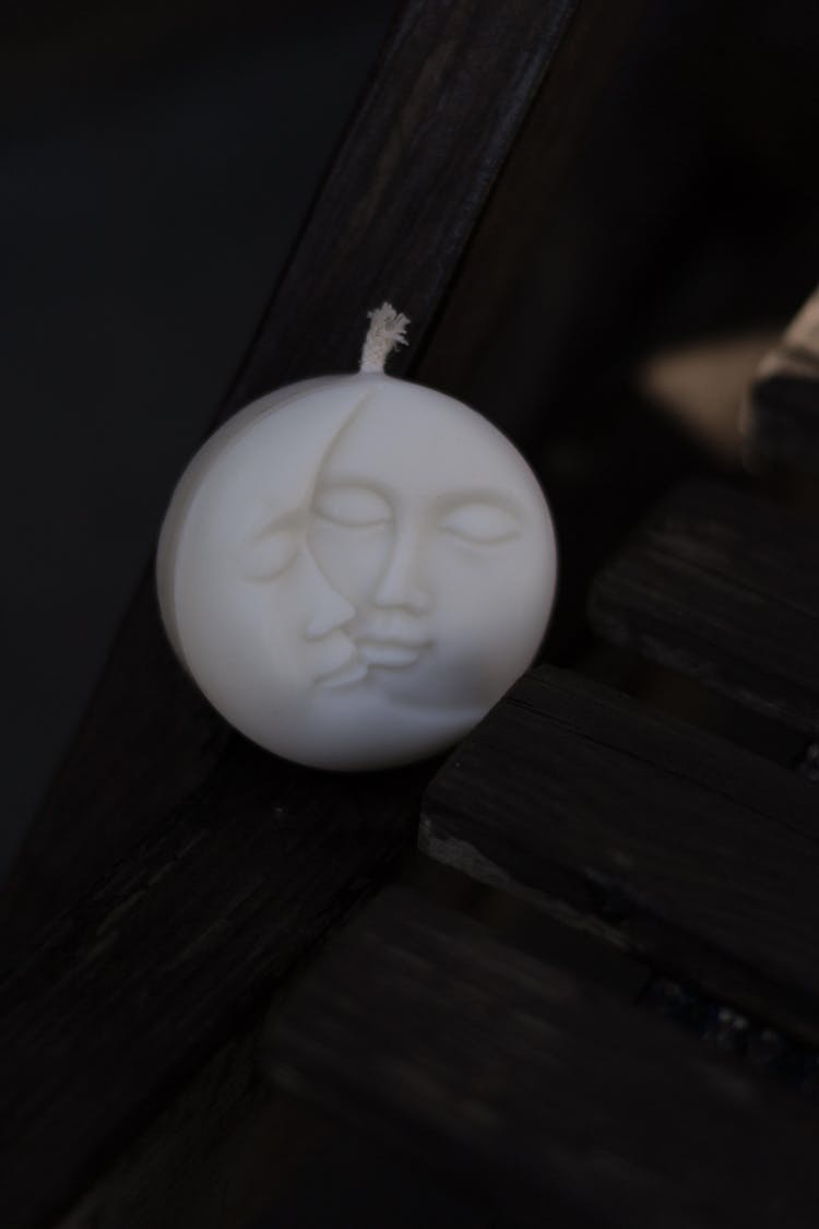 A Candle In The Shape Of A Moon With Faces