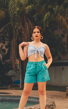 Woman enjoying a casual day by a tropical pool, dressed in summer fashion.