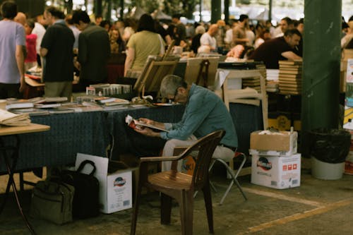 Man Reading a Magazine Sitting at a Book Stall