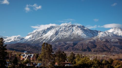 Free Beautiful snow-capped mountains rise above a rural village in Argentina's scenic landscape. Stock Photo