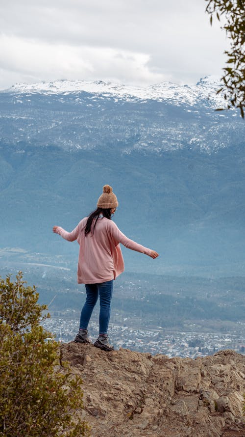 Woman Standing on a Rock and Looking Down at a View 