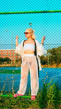 Young woman in stylish summer outfit posing confidently outdoors.