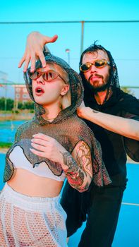 Trendy man and woman with sunglasses and tattoos posing outdoors. Urban style fashion photo.