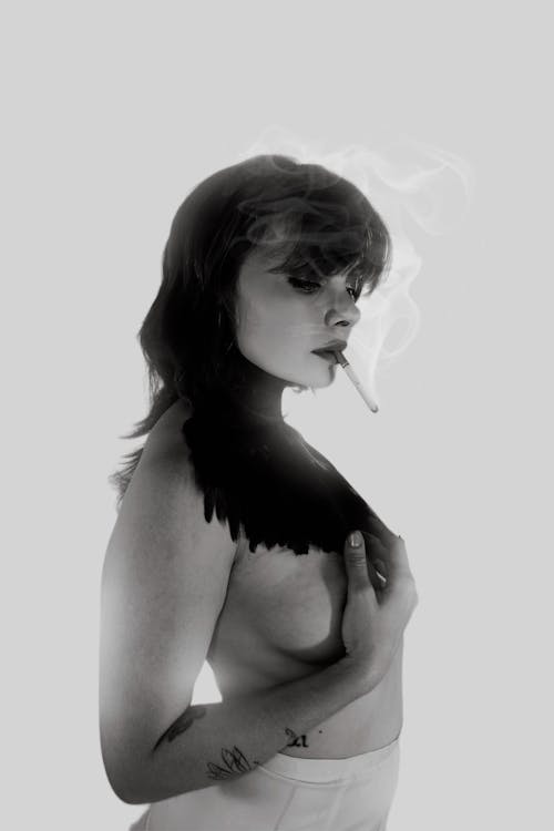 Shirtless Woman with Cigarette in Mouth Covering Breast with Hand