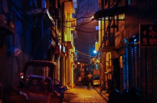 Free A dimly lit alley with a bicycle creates a moody urban scene at night. Stock Photo