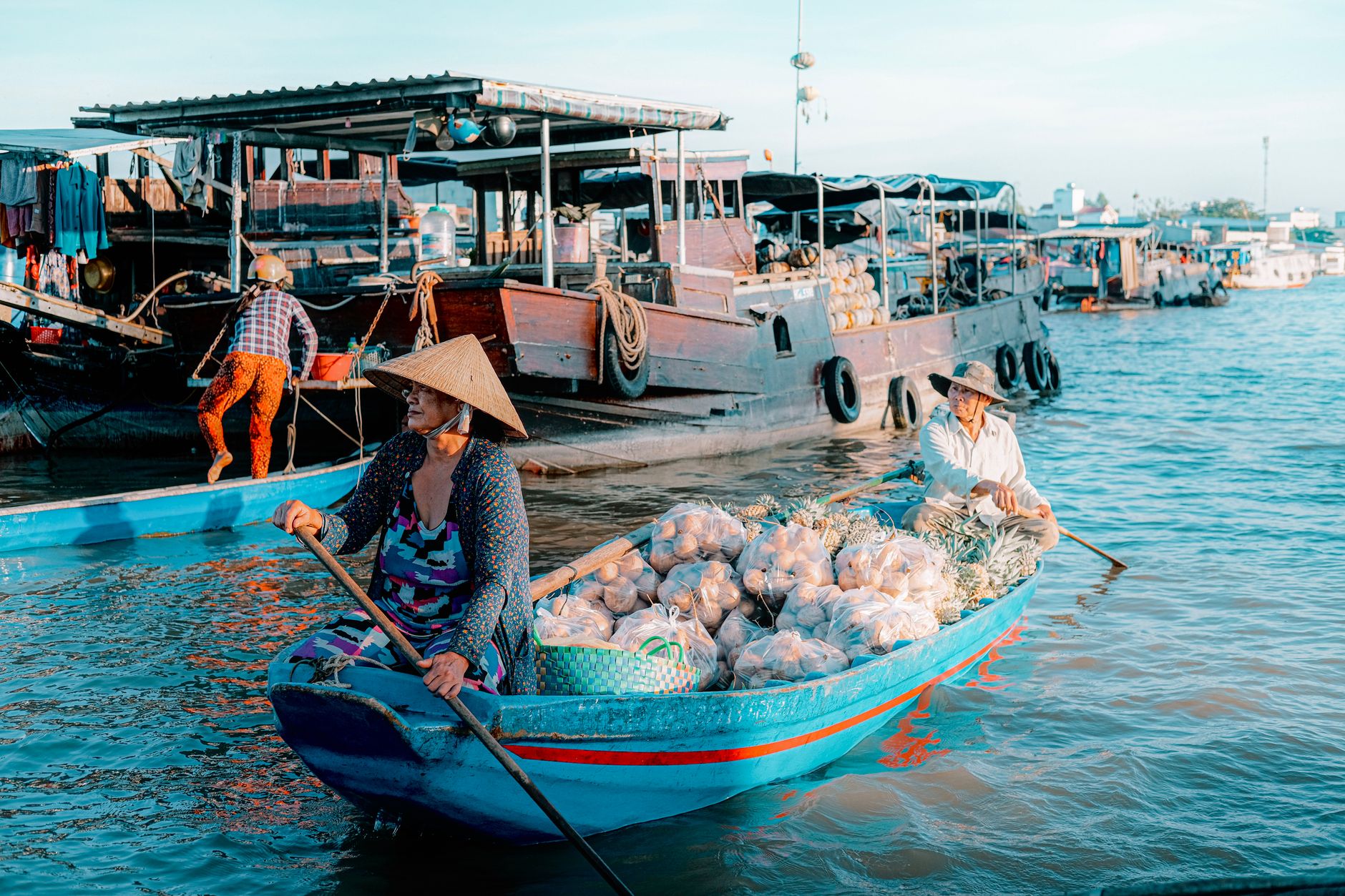Colorful image of a bustling Vietnamese floating market with locals in conical hats on boats.