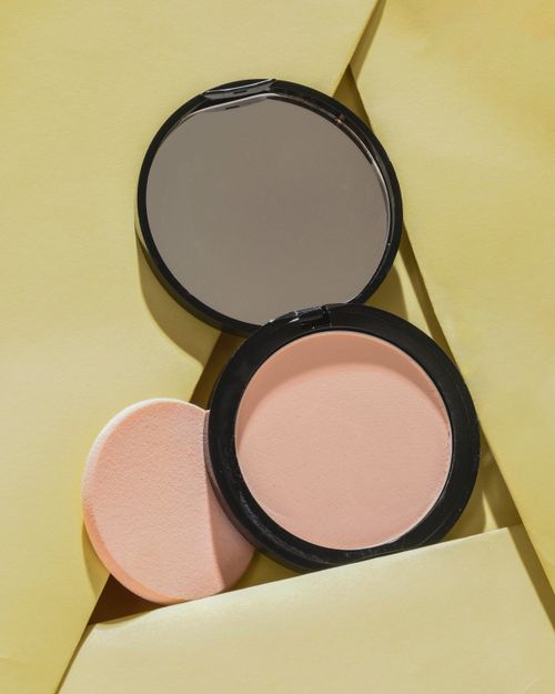 Free Flat lay of compact powder set with mirror on a vibrant yellow background, ideal for beauty concept. Stock Photo