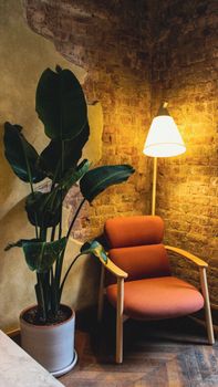 Warmly lit room with an orange armchair, lamp, and indoor potted plant.