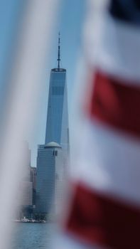 One World Trade Center in New York City with blurred US flag in foreground.
