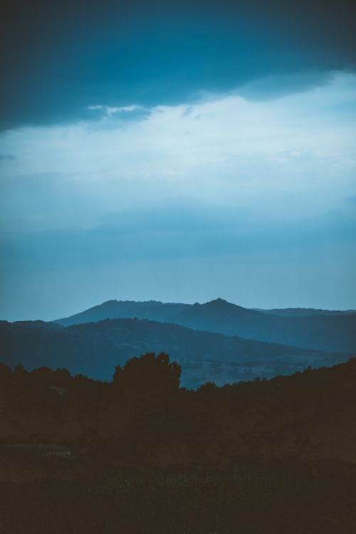 Free A serene view of rolling hills under a dramatic blue sky at dusk, evoking tranquility. Stock Photo