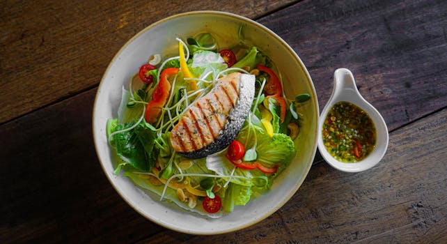 Delicious grilled salmon salad with vibrant fresh vegetables and dressing on the side.